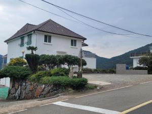 ein weißes Haus am Straßenrand in der Unterkunft Midae Oppa in Geoje