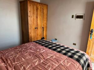 a bedroom with a bed and a wooden cabinet at conixia in San Pedro de Atacama