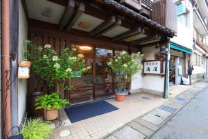 a store front with potted plants outside of a building at Ougiya Ryokan in Toyooka