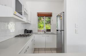 a white kitchen with white cabinets and a window at Villa 31 Tangalooma Beach Front in Tangalooma +10 photos