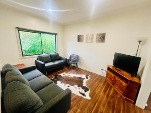 a living room with a couch and a flat screen tv at Wombat Cottage Albury in Albury