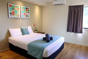 a bedroom with a bed with a blue pillow on it at Weipa Motel Resort in Weipa +15 photos