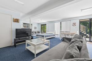 a living room with a couch and a tv at Quandamooka Beach House in Bulwer