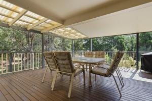 a patio with a table and chairs on a deck at Quandamooka Beach House in Bulwer
