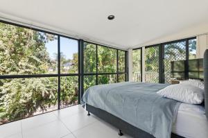 a bedroom with a bed and large glass windows at Quandamooka Beach House in Bulwer