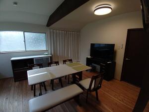 a dining room with a table and chairs and a television at 大宇陀souw創 in Uda