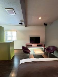 a bedroom with a bed and two chairs and a tv at Hotel JOYCE in Saijō-chō
