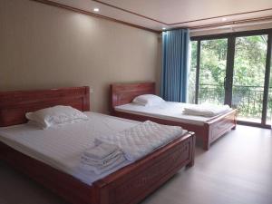 two beds in a room with a window at Homestay Xuân Sơn 2 in Phú Thọ