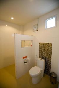 a bathroom with a white toilet and a window at Pharadhevi in Ban Dung