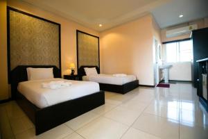 a hotel room with two beds and a television at Pharadhevi in Ban Dung