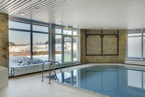 a large swimming pool in a building with windows at Sunday Hotel Willingen in Willingen +61 photos