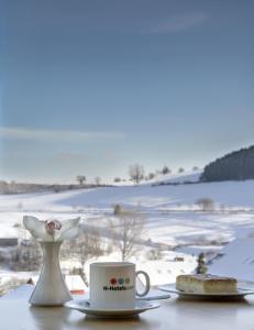einen Tisch mit einer Tasse Kaffee und einem Stück Kuchen in der Unterkunft H+ Hotel Willingen in Willingen