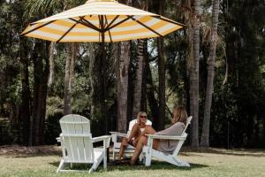 a man and woman sitting in chairs under an umbrella at Tasman Holiday Parks - Kioloa Beach in Kioloa