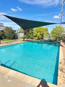 a swimming pool with a shade over it at Charles Sturt Motor Inn in West Wyalong