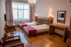 a hotel room with two beds and a mirror at Atlas Hotel in Ulaanbaatar +1 photo