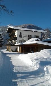 a building covered in snow with a road in front at Gästehaus Bergland in Berwang