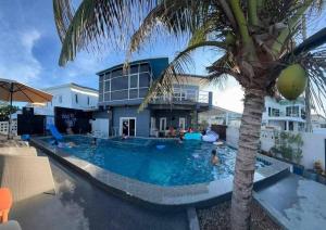 a swimming pool with a palm tree in front of a house at 365Poolvilla Songkhla in Ban Laem Takhian