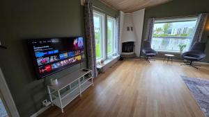 a living room with a flat screen tv and two chairs at Prestelandet Guesthouse in Fredrikstad