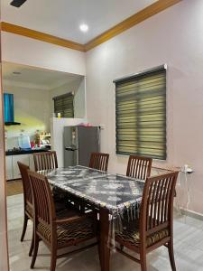 a dining room table with chairs and a kitchen at Ramly Homestay in Kuala Terengganu