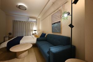 a hotel room with a bed and a blue couch at Haniwa Stay Josai in Nagoya