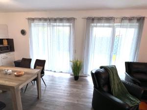 ein Wohnzimmer mit Tisch, Stühlen und Fenstern in der Unterkunft "Nemo" Papenburg ebenerdig rollstuhlgerecht 83 qm Neubau EBK 2 Schlafzimmer 4 Personen Free Wifi in Papenburg