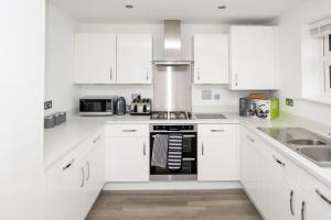a white kitchen with white cabinets and a stove at Cosy 5 Bedroom House With Parking in Chatham