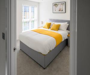 a bedroom with a large bed with yellow pillows at Cosy 5 Bedroom House With Parking in Chatham
