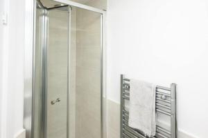 a shower with a glass door in a bathroom at Cosy 5 Bedroom House With Parking in Chatham
