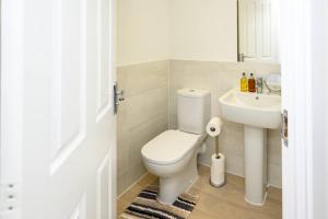 a white bathroom with a toilet and a sink at Cosy 5 Bedroom House With Parking in Chatham +25 photos