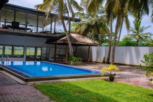 a swimming pool in front of a house with palm trees at LHK Dream Resort Matara in Palatuwa