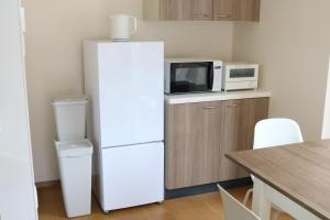 a white refrigerator with a microwave on top of it at 郡上八幡 貸宿 GujoHachiman Kashiyado ICHI in Gujo