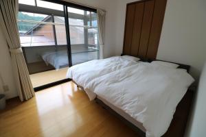 a bedroom with a white bed and a large window at 郡上八幡 貸宿 GujoHachiman Kashiyado ICHI in Gujo