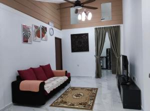 a living room with a couch and a tv at SELAMA Merdeka Homestay 2-6pax in Selama