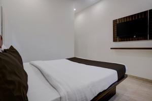 a white bed in a room with a tv at Collection O IIM Mumbai Formerly Green View in Mumbai