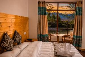 a bedroom with a bed and a table and a window at The Nature Residency - A Riverside Resort in Leh in Leh