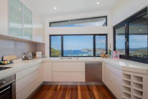 a kitchen with white cabinets and a large window at Avoca Infinity - Expansive Haven with Ocean Panorama in Terrigal