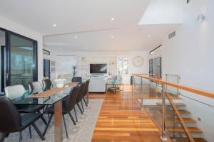 a dining room and living room with a table and chairs at Avoca Infinity - Expansive Haven with Ocean Panorama in Terrigal
