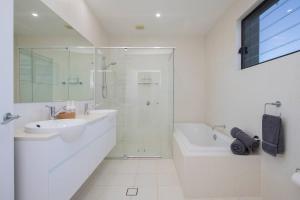 a white bathroom with a shower and a sink and a tub at Avoca Infinity - Expansive Haven with Ocean Panorama in Terrigal +28 photos