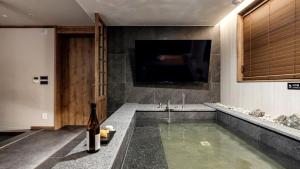 a room with a pool with a television and a bottle of wine at Anook Resort & Spa Busan Haeundae in Busan