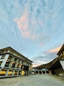 a large building with a cloudy sky in the background at Dema Rresort in Paro