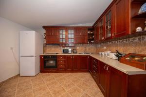 a kitchen with wooden cabinets and a white refrigerator at Perfect Seaview Two-bedroom Apartment Tramontana in Dobra Voda