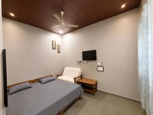 a bedroom with a bed and a chair and a tv at Hotel Vasundhara in Garot