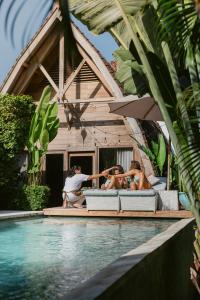 a group of people sitting next to a swimming pool at Karma House Ungasan in Jimbaran