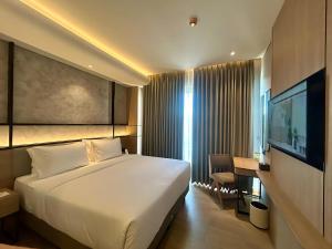 a hotel room with a bed and a desk and a television at Kaloka City Hotel Bima in Bima
