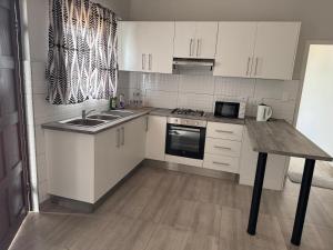 a kitchen with white cabinets and a wooden table at Gottys Lagoon Stay in Walvis Bay