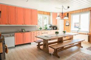 a kitchen with orange cabinets and a wooden table at Kiulukka mökki in Jyväskylä