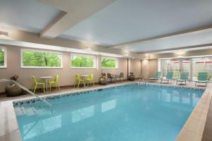 a pool in a hotel room with chairs and tables at Home2 Suites By Hilton Silver Spring in Silver Spring