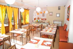 a restaurant with tables and chairs and yellow curtains at Hotel Norte in Villa Gesell