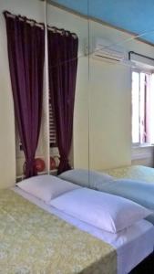 two beds in a bedroom with purple curtains at appartamento " il piccolo ' in Rome