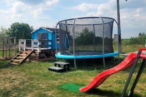 a playground with a trampoline in the grass at Comfortable holiday home, pool, sauna, jacuzzi in Brzuze